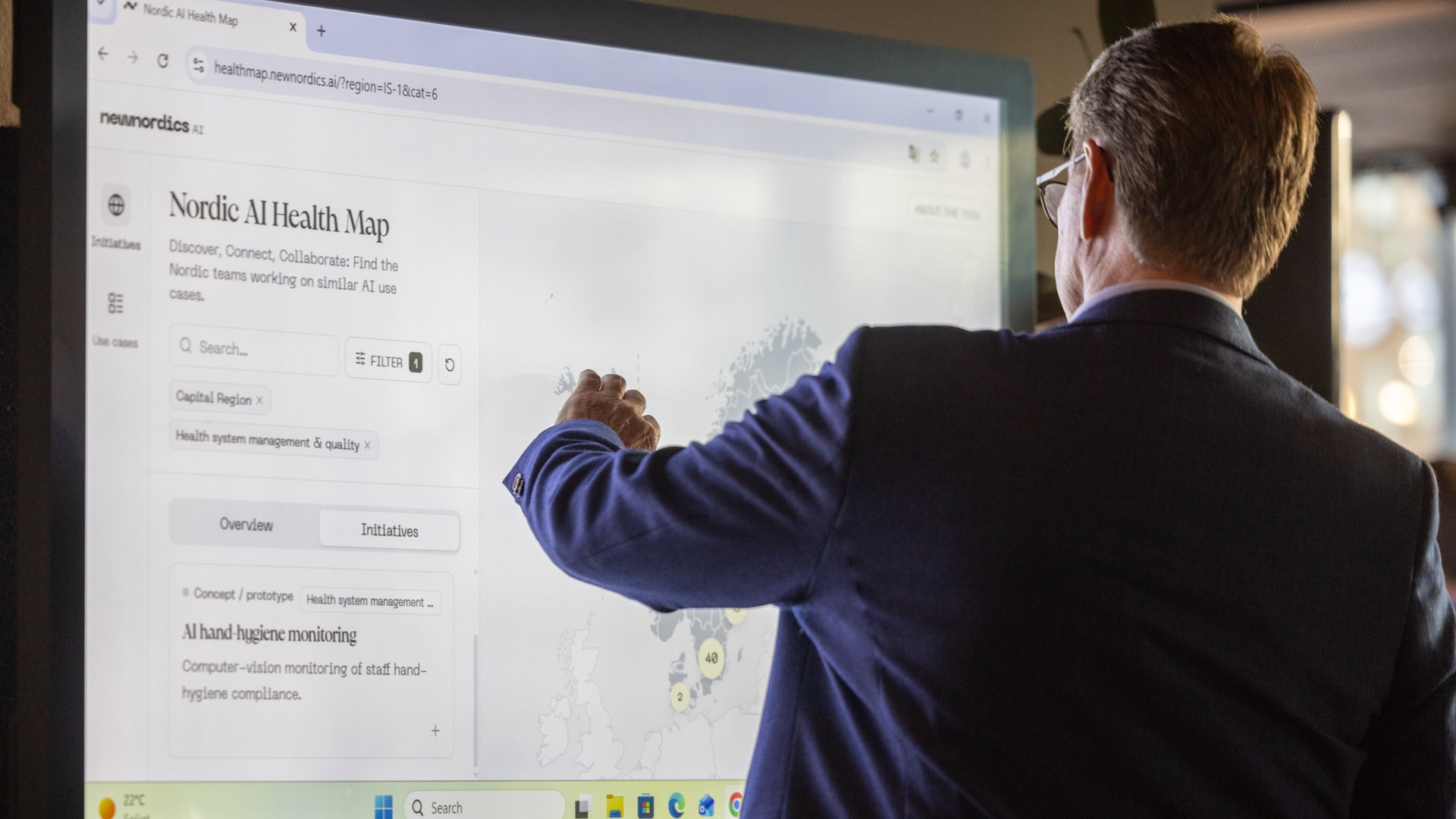 A man standing in front of a TV-monitor of the Nordic AI Health Map.