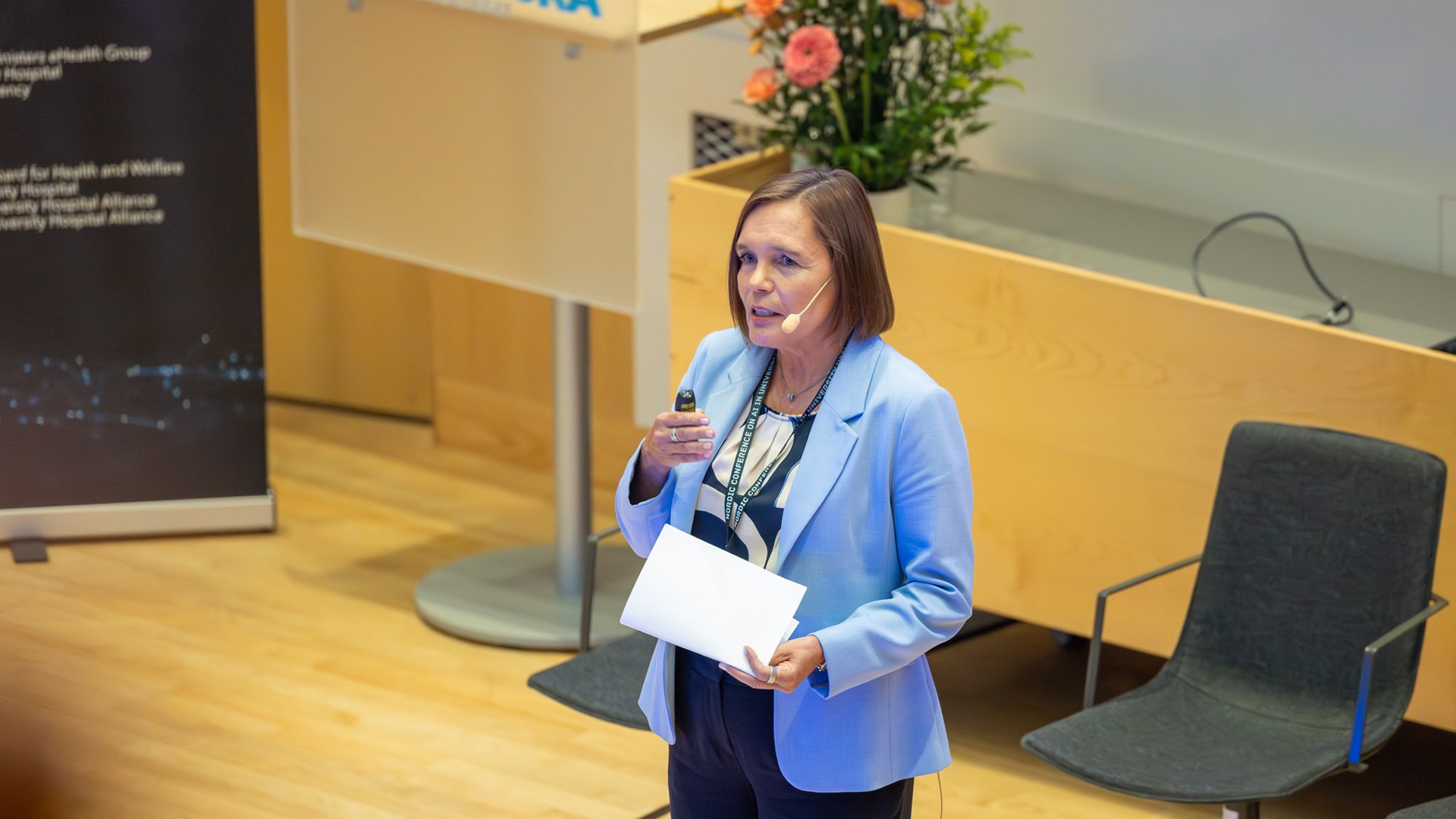 Saila Rinne standing in front of a podium holding a piece of paper.