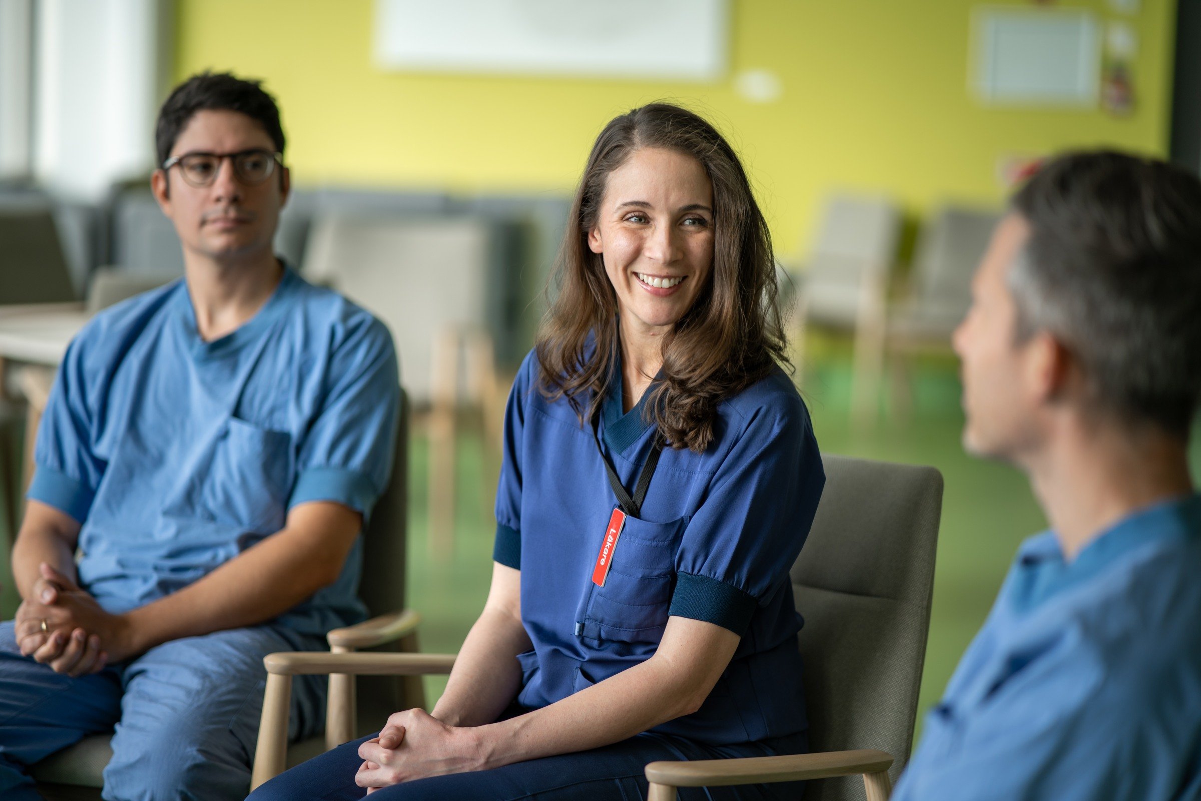 A group of people/fellows sitting in chairs in a room.