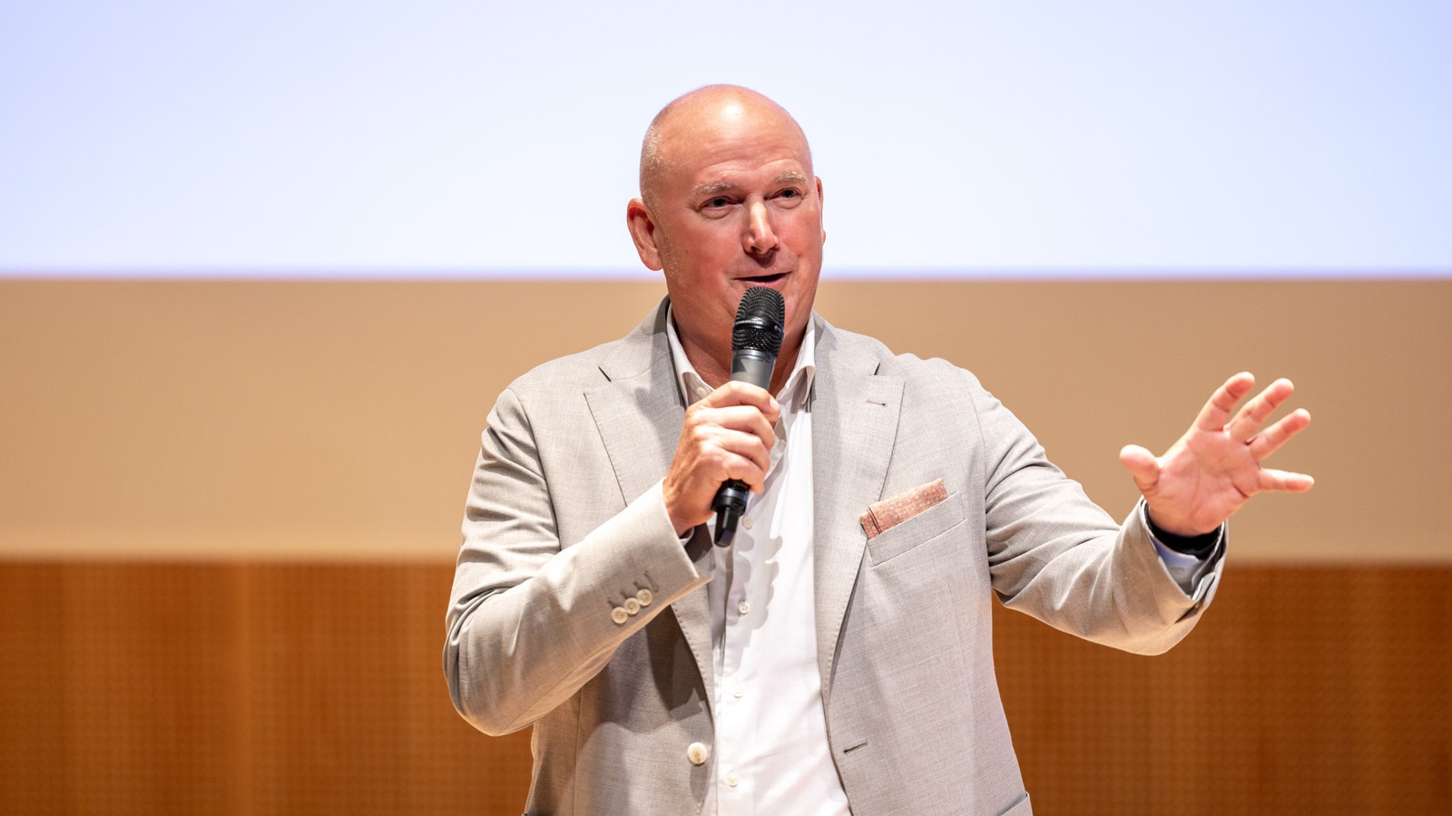 A man in a suit speaking into a microphone.