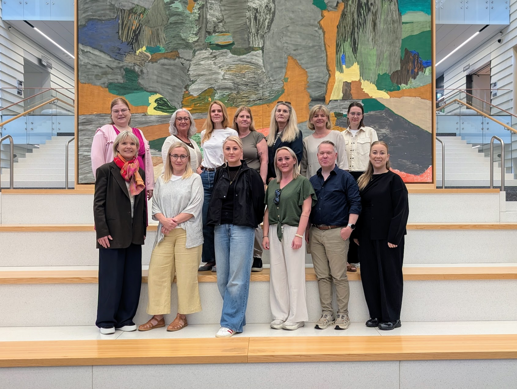 A group of people standing in front of a painting.