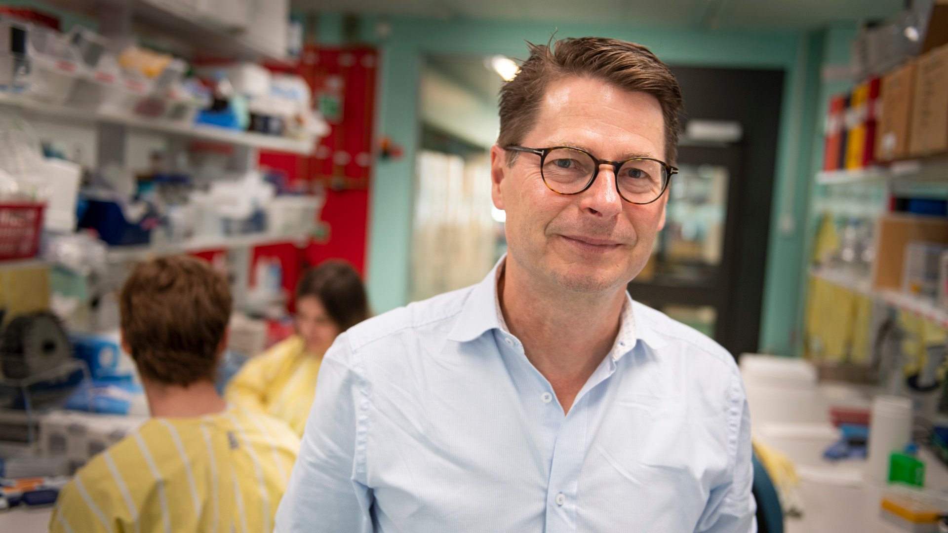 A man in a blue shirt and glasses standing in a pharmacy.