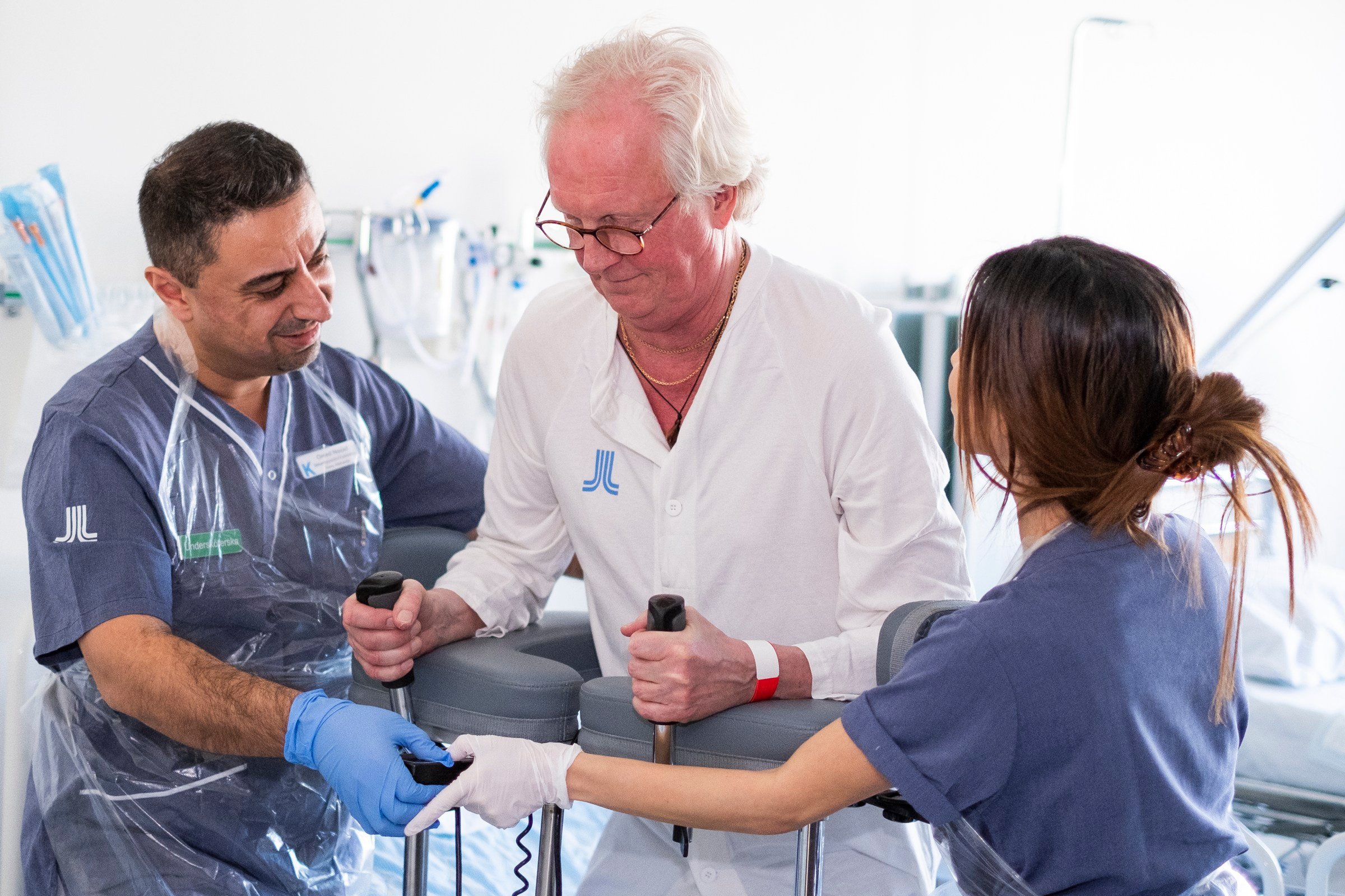 two nurses helping older man to stand up with help of walker