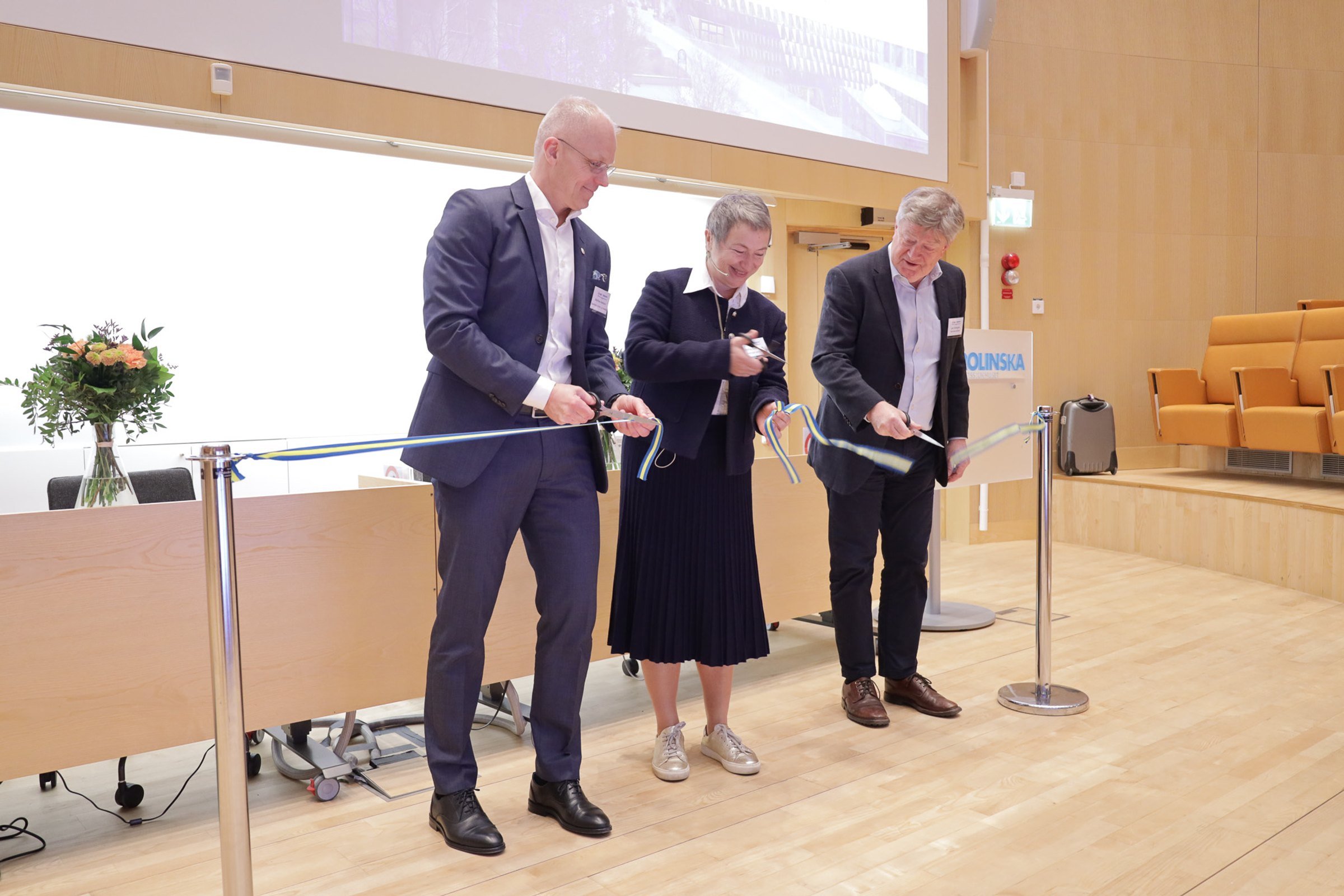 three people cutting the ribbon on stage