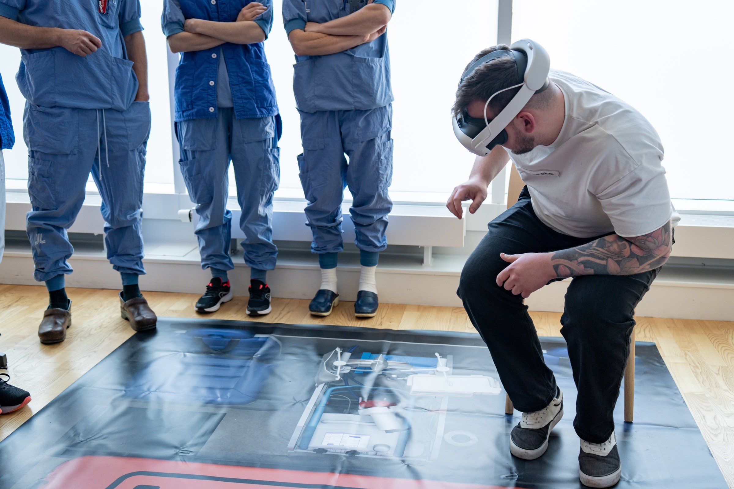 A man trying XR technology in front of people in medical scrubs.